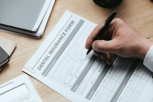 man's hand filling out dental insurance form