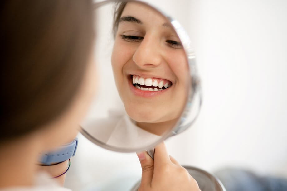 young woman looking in mirror and smiling