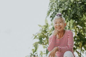 A woman smiles under a tree