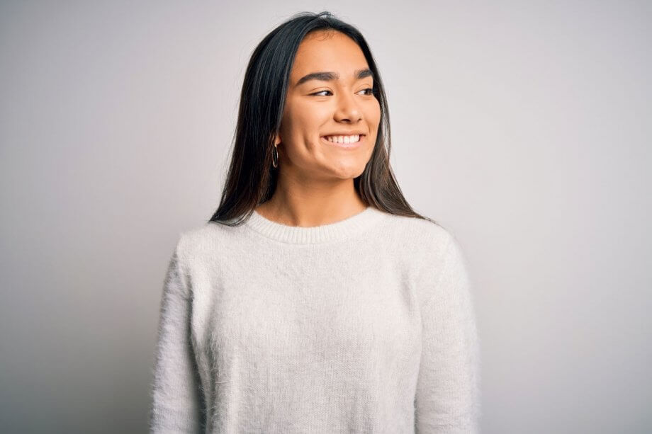 smiling woman in white sweater standing against white background